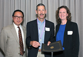 Dr. Richard Presland (center) is inducted by Dr. Daniel Chan and Dr. Flake of the faculty. 