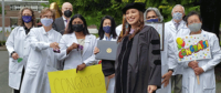 Cheered on by faculty members, Dr. Lindsey Montileaux Mabbutt celebrates her graduation from the School of Dentistry. Dr. Bea Gandara, holding a “Congrats” sign, is at far right.