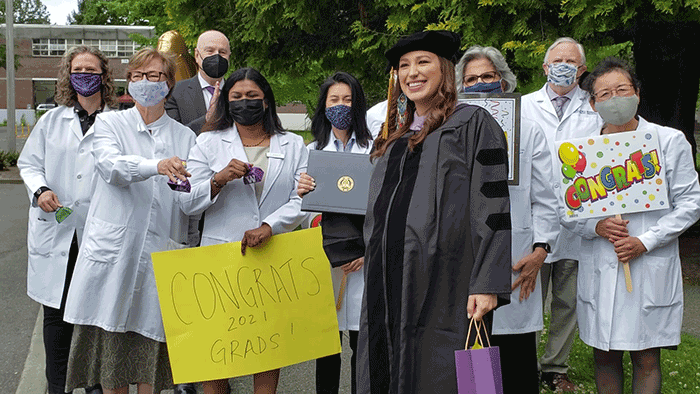 Cheered on by faculty members, Dr. Lindsey Montileaux Mabbutt celebrates her graduation from the School of Dentistry. Dr. Bea Gandara, holding a “Congrats” sign, is at far right.