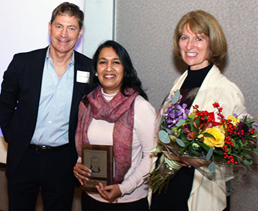 3 people with flowers and award