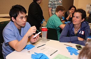 Dental student Nguyen Tung describes how fluoride varnish is applied as medical student Kaitlyn Mulhern listens.