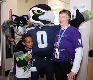 Harry the Husky and Blitz huddle up with Dr. Rebecca Slayton, and patient Yabets Hailemariam, 8, of Shoreline.